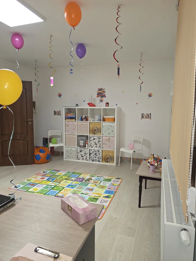 Sala de joacă cu bibliotecă, covor cu alfabet și decorațiuni festive de inaugurare
