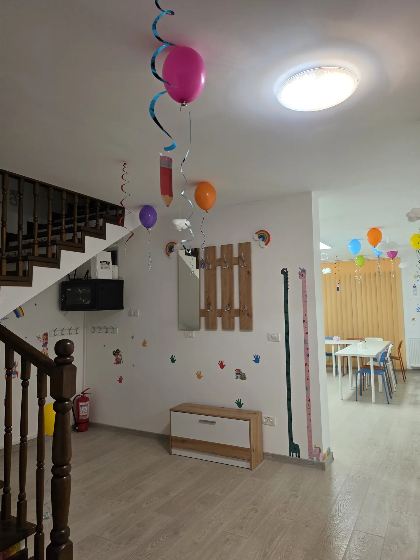 Holul de la intrare cu scara din lemn, decorat cu baloane la inaugurare