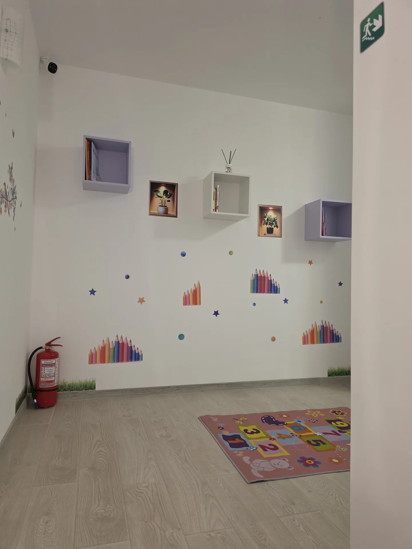 Colț de relaxare cu covoraș de joacă și rafturi decorative pe perete