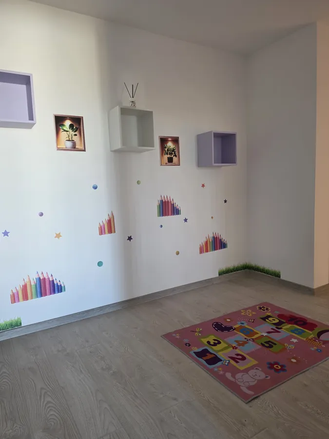 Colț de joacă cu covoraș de șotron și rafturi decorative