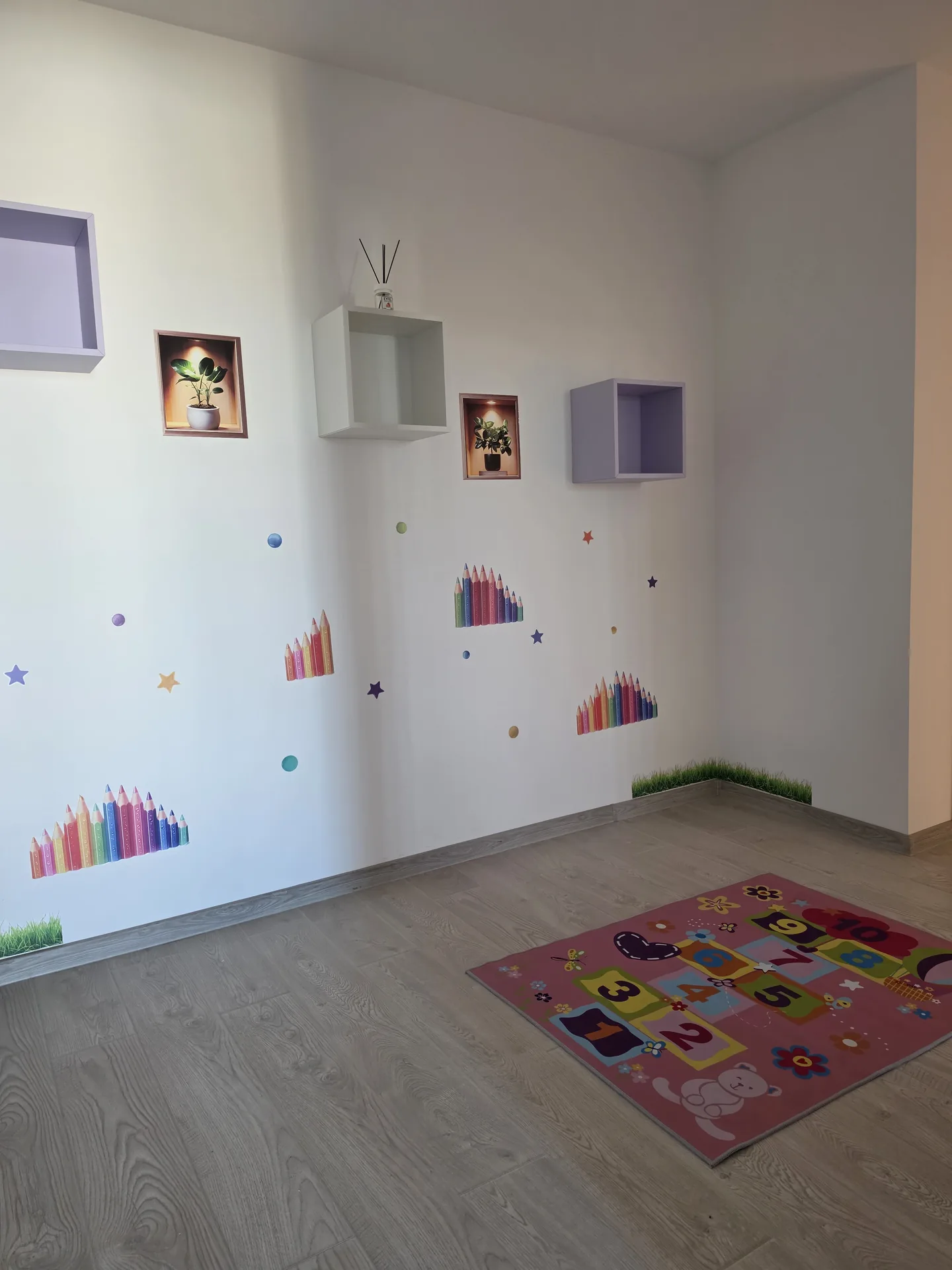 Colț de joacă cu covoraș de șotron și rafturi decorative